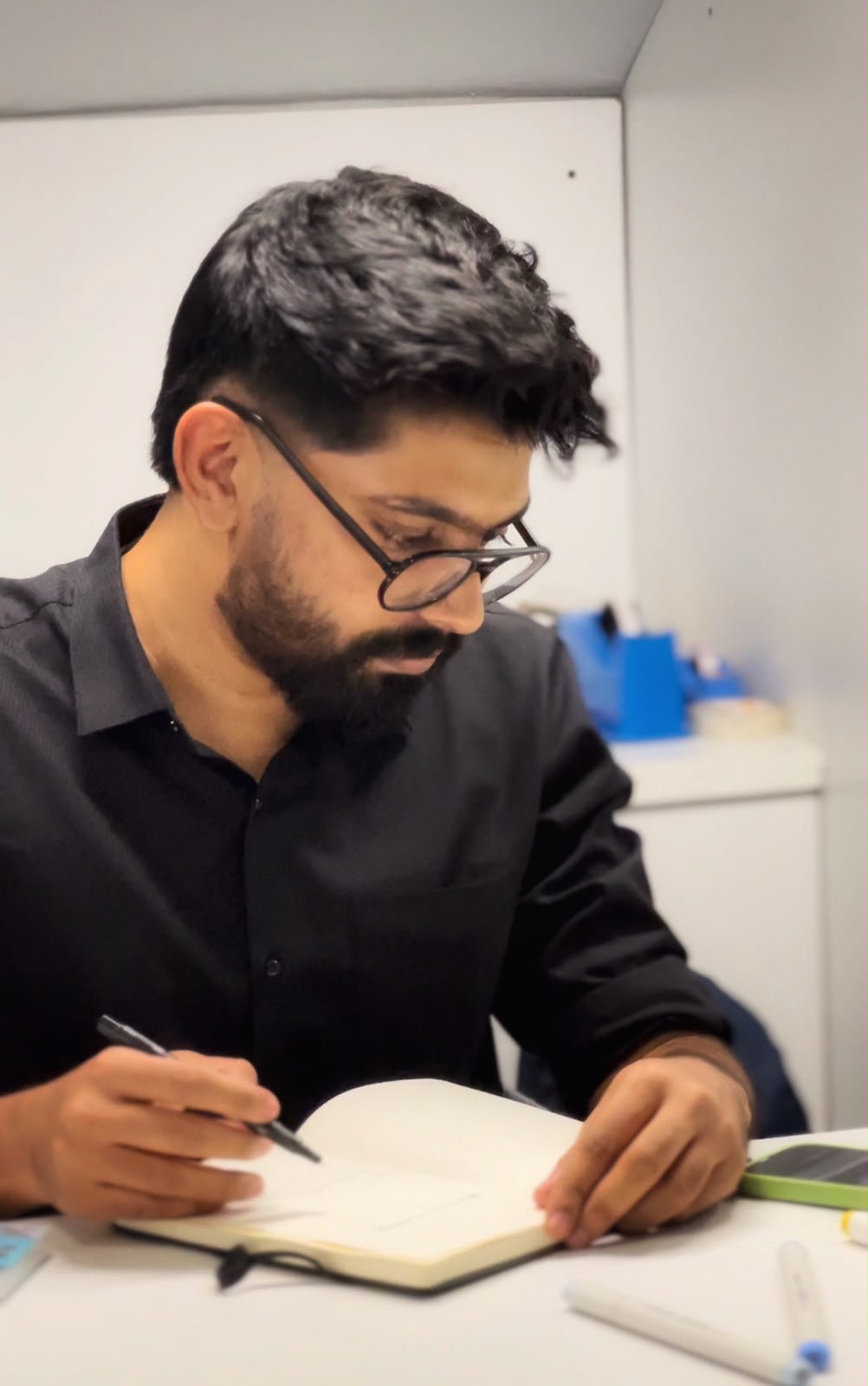 Deepak seated at a table, drawing in a sketchbook