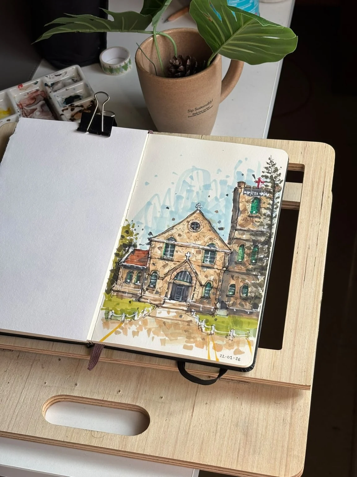 Open sketchbook showing a finished architectural drawing on a working table